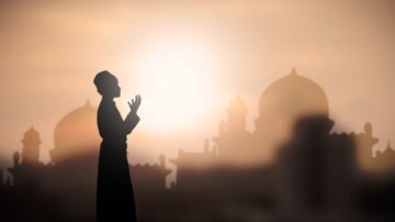 صورة ظلية لشخص يصلي في وقت الغروب، مع خلفية تضم معالم مساجد مميزة. تعكس الصورة أجواء الروحانية والسكينة.
