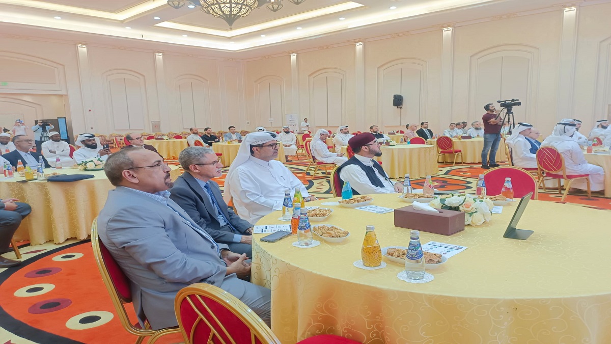 حدث تجاري يجمع مجموعة من الأشخاص في قاعة احتفالات. يوجد طاولات مزينة بموائد صغيرة تحتوي على مشروبات ووجبات خفيفة. الحضور يرتدي ملابس تقليدية وعصرية، مع التركيز على النقاشات والفعاليات.