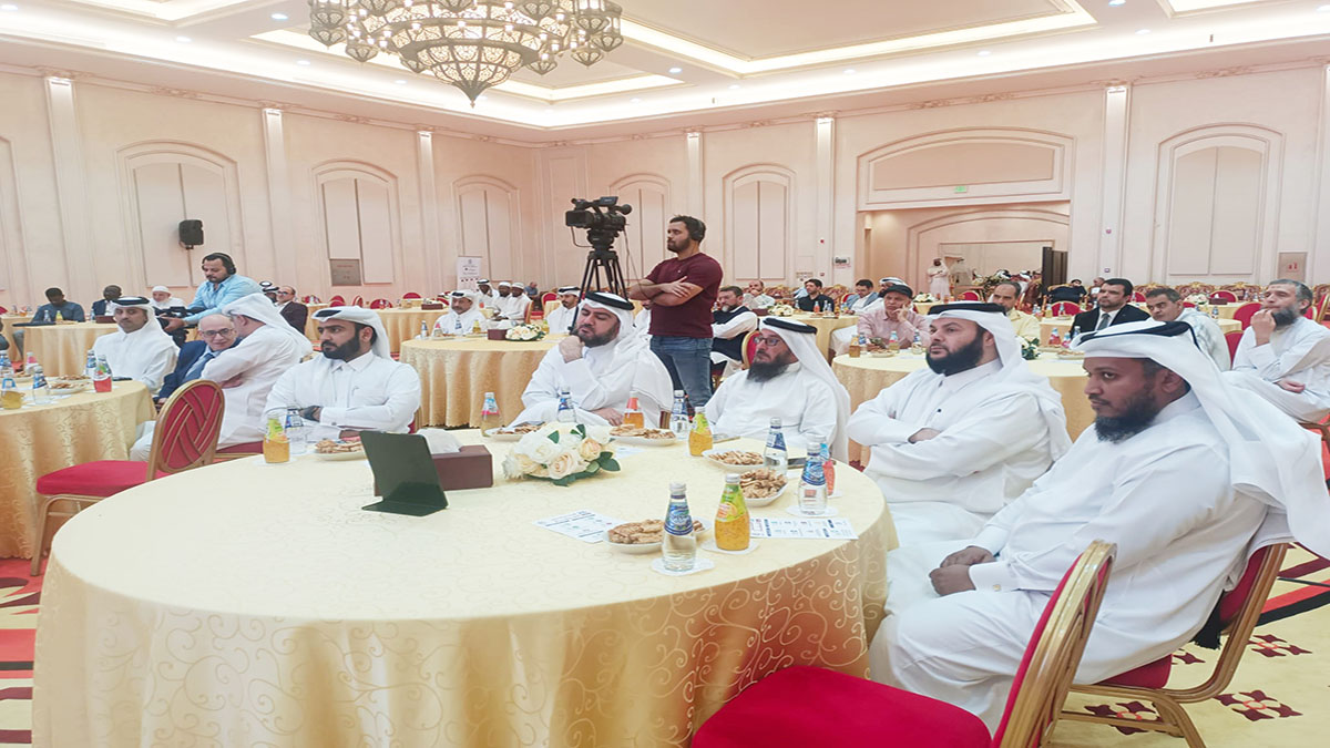 تجمع حاشد لرجال الأعمال في قاعة فاخرة، حيث يجلس الحضور حول طاولات دائرية مغطاة بمفارش ذهبية. يتحدث بعض المشاركين بينما يركز الآخرون على المتحدث. تظهر الكاميرات والمعدات الإعلامية في الخلفية، مما يشير إلى تغطية الحدث.