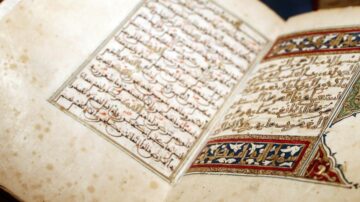 Close-up of an ancient manuscript page featuring intricate Arabic calligraphy and colorful decorative elements. The text is written in a traditional style, showcasing the craftsmanship of historical bookmaking.