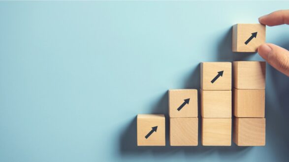 كتل خشبية مرتبة بشكل متزايد، تشير الأسهم إلى الاتجاه التصاعدي. خلفية زرقاء تضيف إحساسًا بالهدوء والتفاؤل.