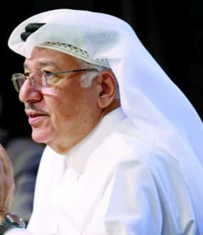 رجل مسن يرتدي الثوب العربي التقليدي والغترة، يتحدث بجدية في حدث رسمي. تعكس تعابير وجهه الحكمة والخبرة.