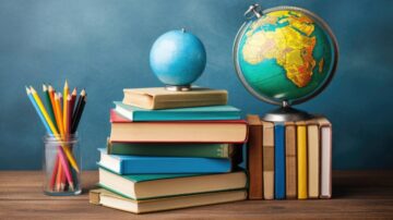 كتب ملونة مكدسة على طاولة خشبية، معكرة زجاجية تحتوي على أقلام ملونة، وكرة أرضية تعرض قارة أفريقيا، مع خلفية زرقاء.