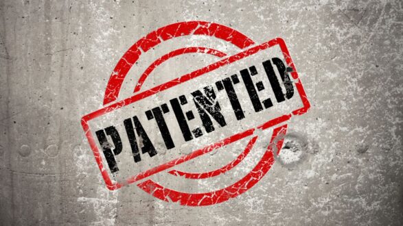 ختم "محمي ببراءة اختراع" باللون الأحمر على خلفية خرسانية رمادية، يعكس مفهوم الملكية الفكرية والابتكار.