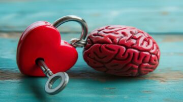 صورة توضح دماغًا بشريًا مجسمًا باللون الأحمر بجانبه قفل على شكل قلب ومفتاح. الخشب خلفية زرقاء، تعكس موضوعات الحب والعقل.