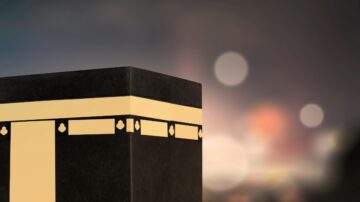 Black Kaaba with gold detailing, illuminated against a blurred background of lights, symbolizing Islamic pilgrimage and spirituality.