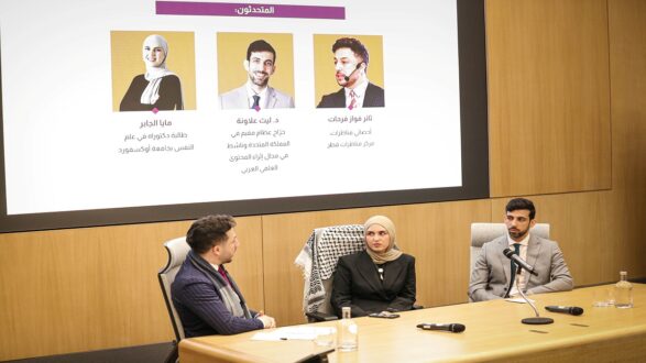 حدث نقاش حول الابتكار في التكنولوجيا، مع ثلاثة متحدثين يجلسون في طاولة مستديرة. المتحدث الأول يرتدي بدلة رسمية، بينما ترتدي المتحدثة الثانية حجابًا وبدلة، والمتحدث الثالث يرتدي أيضًا بدلة. خلفهم شاشة تعرض معلومات عن المتحدثين.