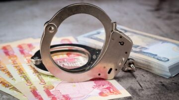 Handcuffs resting on a pile of colorful banknotes, symbolizing crime and law enforcement.