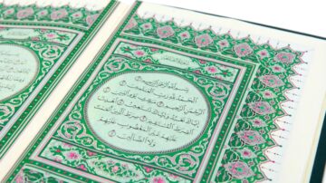Open Quran page featuring intricate floral designs and Arabic calligraphy, highlighting verses in a decorative layout. The vibrant green and pink colors enhance the visual appeal of the sacred text.