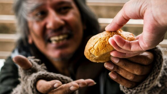 رجل مسن مبتسم يتلقى خبزًا من يد شاب، مع التركيز على اللحظة الإنسانية للتبادل، تعبير عن العطاء والمشاركة، خلفية غير واضحة.