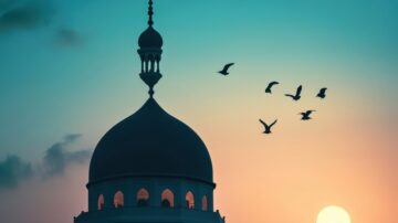 صورة لسماء غروب الشمس مع silhouette لقبة مسجد، حيث تحلق طيور في الأفق. الألوان تشمل درجات الأزرق والبرتقالي، مما يخلق مشهداً هادئاً وجميلاً.