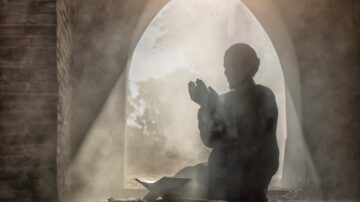 Silhouette of a person praying in a misty, arched window setting, creating a serene and contemplative atmosphere. Natural light filters through, enhancing the spiritual mood.