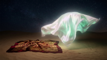 شال حريري يتطاير في الهواء فوق سجادة مزخرفة على رمال الصحراء تحت سماء مرصعة بالنجوم.