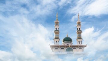 Mosque with three minarets and a green dome against a blue sky with fluffy clouds.