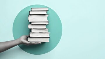 كتاب مكدس على قاعدة دائرية باللون الأزرق، مع يد تحمل الكتب، تعبير عن المعرفة والثقافة.