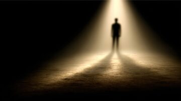 شخص مظلم يقف في مركز شعاع ضوء قوي، محاط بظلال داكنة. تبرز الإضاءة الشكل الغامض، مما يخلق جوًا من الغموض والتوتر.