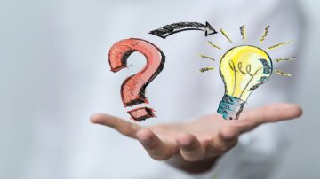 يد ترفع علامة استفهام حمراء ورمزا لمصباح مضيء أصفر مع سهم يربط بينهما، مما يرمز إلى فكرة التحول من التساؤلات إلى الحلول الإبداعية.