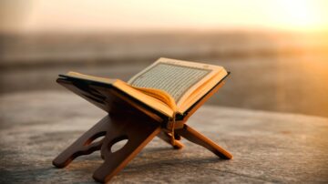 مصحف مفتوح على حامل خشبي وقت الغروب يجسد خصائص القرآن الكريم ونوره