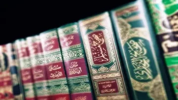 Collection de livres religieux en arabe, présentant des couvertures ornées et des titres dorés, alignés sur une étagère. Les volumes sont soigneusement rangés, mettant en valeur leur design traditionnel et leur importance culturelle.