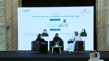 ندوة حول التربية والابتكار المعرفي في التعليم، تتضمن ثلاثة متحدثين، واحد منهم يرتدي ثوباً تقليدياً. يوجد خلفية تحتوي على نص يتحدث عن التحولات في التعليم.