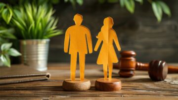 شخصيتان ورقيتان تمثلان رجلًا وامرأة، واقفتان على قاعدة خشبية، مع مطرقة قاضي في الخلفية ونبات أخضر، تعكس موضوع القانون والعدالة.