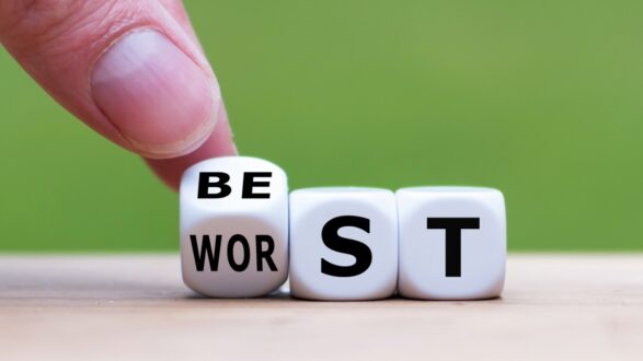 صورة تحتوي على يد تشير إلى مكعبات تحمل الكلمات "BE" و"WORST" و"ST" مع التركيز على التحول من الأسوأ إلى الأفضل. تعبر عن مفهوم التغيير والتحسين.