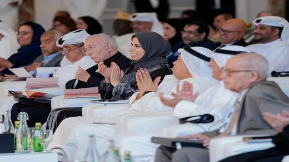 حضور متنوع في فعالية ثقافية، مع رجال ونساء يرتدون الزي العربي التقليدي، يبتسمون ويصفقون، يعبرون عن التقدير والتفاعل الإيجابي.