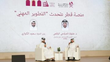 منصة قطر تتحدث عن التطوير المهني، تتضمن نقاشًا بين شخصين يرتديان الزي القطري في حدث تنظمه وزارة الثقافة، مع خلفية تحمل شعار الوزارة.