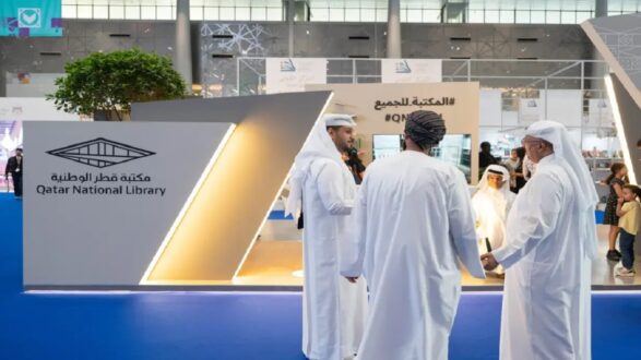 مكتبة قطر الوطنية في معرض ثقافي، مع زوار يرتدون الملابس التقليدية. يظهر تصميم حديث للمعرض مع شعار المكتبة.