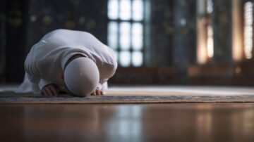 Muslim man demonstrating Iqamat as-Salah by performing sujud on a prayer rug inside a mosque, reflecting deep devotion, faith, and spirituality during Islamic worship.