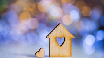 Sound heart (Qalbun Saleem): Wooden house and heart figurines on a blurred bokeh background, symbolizing love, home, warmth, family, and cozy living.