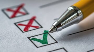 قلم فضي يتسطح على ورقة تحتوي على مربعات اختيار، حيث تم وضع علامة صح باللون الأخضر في أحد المربعات بينما تم وضع علامات خطأ باللون الأحمر في مربعات أخرى.