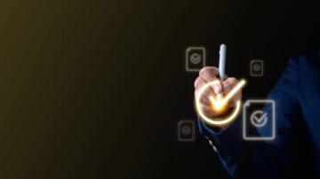 يد عُليا تحمل قلمًا وتظهر علامة تحقق مضيئة على خلفية داكنة، مع أيقونات تحقق بسيطة حولها، مما يرمز إلى النجاح أو إتمام المهام.