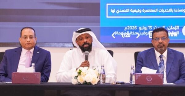 اجتماع لمناقشة استراتيجية تطوير السياحة، حيث يتحدث رجل يرتدي عباية وغترة، محاطًا برجلين يرتديان بدلات. خلفهم شاشة تعرض معلومات حول الحدث.