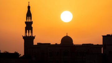 Silhouette of a mosque with a minaret and dome against a vibrant orange sunset, highlighting the peaceful ambiance of the evening sky and inspiring viewers to give faith a chance.