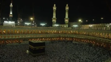Vue nocturne de la Kaaba à La Mecque, entourée de milliers de pèlerins en train d'effectuer le Tawaf. Les minarets illuminés et l'architecture majestueuse de la mosquée présentent un cadre spirituel impressionnant.