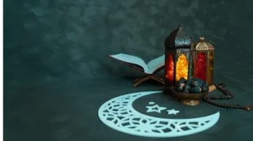 Lampe marocaine illuminée avec des motifs colorés, un Coran ouvert et un bol de perles de prière, le tout reposant sur un fond sombre avec une silhouette de croissant de lune et d'étoiles. Idéal pour représenter des thèmes culturels ou religieux.