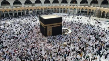 Vue aérienne de la Kaaba à La Mecque, entourée d'une immense foule de pèlerins en vêtements blancs lors du Hajj, avec les arches de la mosquée en arrière-plan.