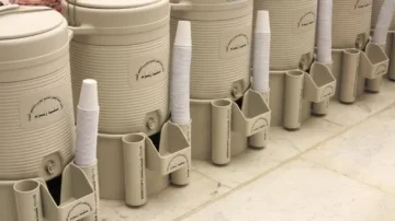 Distributeurs de boissons en plastique beige avec gobelets en papier, alignés sur un sol en marbre.