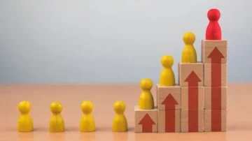 Graphique représentant une montée en compétences avec des figurines en bois. Des figurines jaunes symbolisent la progression, tandis qu'une figurine rouge se trouve au sommet. Les flèches sur les blocs indiquent une amélioration continue. Idéal pour illustrer le succès et le développement personnel.