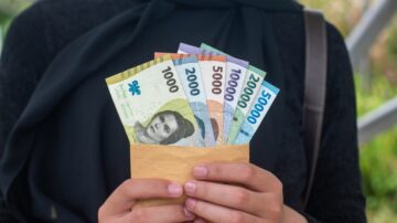 إمرأة تحمل مظروفًا يحتوي على مجموعة من الأوراق النقدية المختلفة