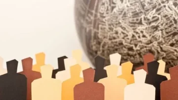 Silhouettes en papier de personnes de différentes couleurs devant un globe terrestre, symbolisant la diversité et l'unité mondiale.