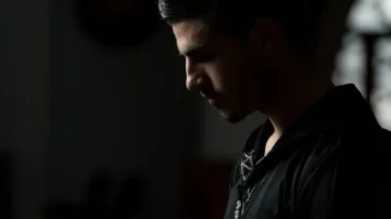 Homme pensif en silhouette, éclairage sombre mettant en valeur son profil, ambiance contemplative.