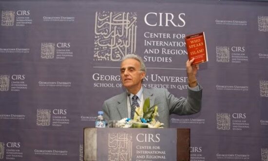 رجل يحمل كتابًا بعنوان "من يتحدث عن الإسلام" أثناء إلقاء محاضرة في مركز الدراسات الدولية والإقليمية بجامعة جورجتاون في قطر. خلفية الصورة تحمل شعار المركز.