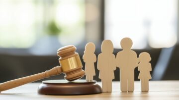 مطرقة قانونية خشبية بجانب تماثيل خشبية تعكس عائلة، تشير إلى موضوع العدالة والقانون، مع خلفية مشوشة لإبراز التركيز على العناصر الرئيسية.