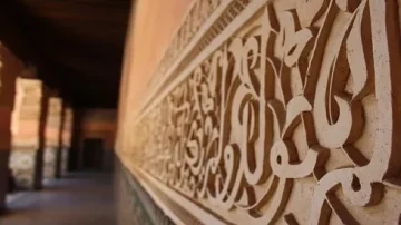 Détail d'un mur orné de motifs arabesques en plâtre, mettant en valeur l'architecture traditionnelle. La perspective met en avant la profondeur et la texture des motifs.