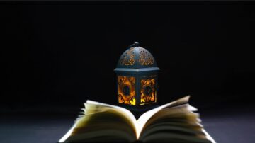 Islamic legislation: An open Quran inside a mosque set against a dark black background, illuminated in low light