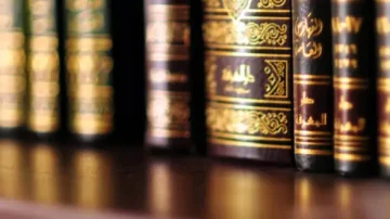 Livres anciens en cuir ornés de dorures sur une étagère en bois, affichant des titres en arabe. Ambiance studieuse et culturelle, idéale pour les amateurs de littérature et d'histoire.