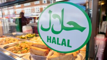 علامة تشير إلى طعام حلال في متجر، مع توضيح كلمة "حلال" باللغة العربية والإنجليزية، محاطة بإطار دائري أخضر.