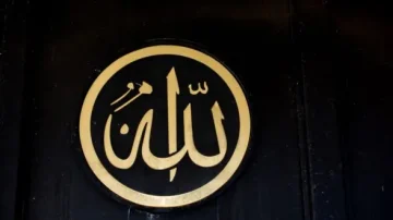 Inscription en or du mot "Allah" dans un cercle noir, affichée sur une surface en bois sombre. Design simple et élégant, symbolisant la foi islamique.